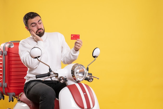노란색에 은행 카드를 들고 가방에 오토바이에 앉아 젊은 집중된 여행 남자와 여행 개념