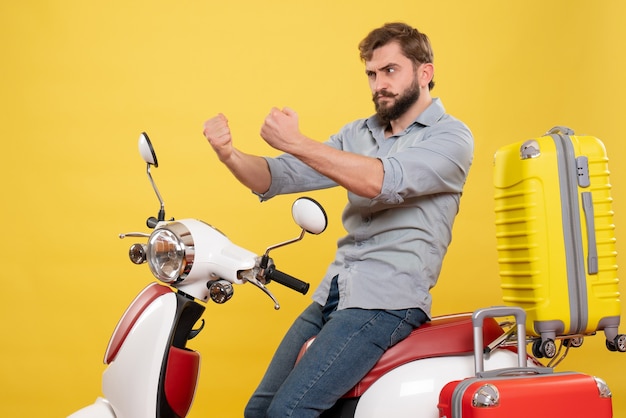 Travel concept with young emotional angry bearded man sitting on motocycle on it on yellow 