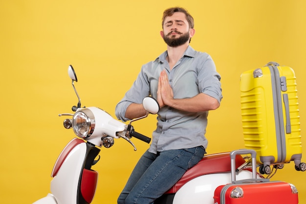 Travel concept with young emotional bearded man sitting on motocycle on it dreaming on yellow 