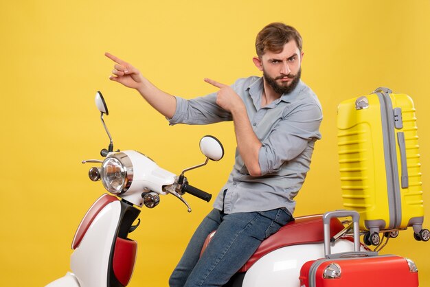 黄色の上向きにその上にオートバイに座っている若い感情的なひげを生やした男と旅行の概念