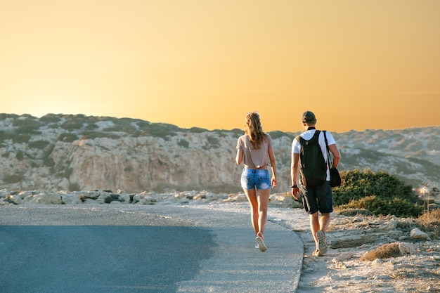 A A A A A A A A A A A Aƒ Travel Girlfriends Walking Along A Highway Against A Background Of Sunset And Sea Coast Travel And Freedom Adventures And Directions For Travel Premium Photo