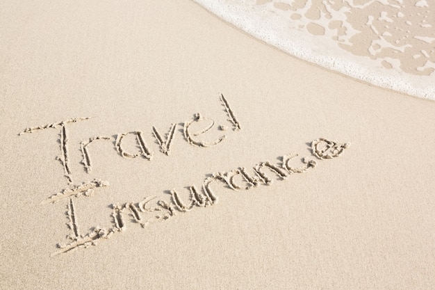 Travel Insurance written on sand