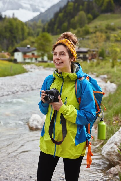 Travel and outdoor activities concept. Optimistic lovely female hiker walks by small mountain stream