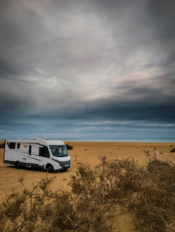 海の見えるビーチにキャンピングカーを駐車して休暇を過ごすライフスタイル-自然の中でのrv車キャンプカーキャンプ。休日のコンセプトは、海と空を背景に大きなバンを無料で輸送します