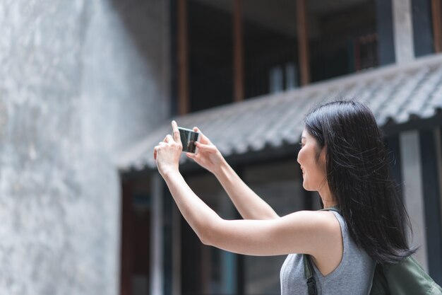 中国の北京で休暇旅行を過ごしながら写真を撮るために携帯電話を使用して旅行者アジア女性