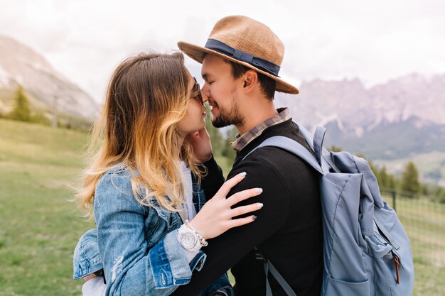 Traveler in brown hat gently kisses his girlfriend during trip around Italy in vacation