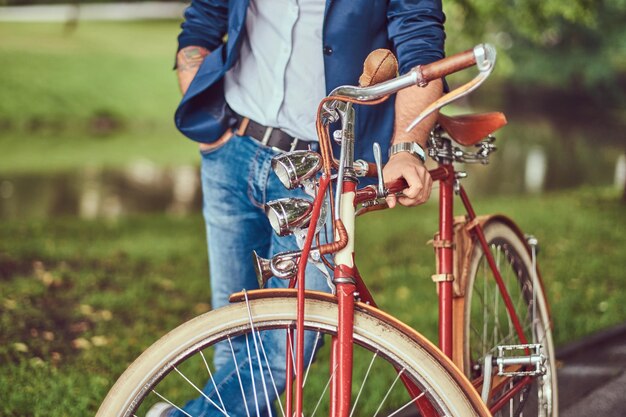 A traveler dressed in casual clothes with a backpack, relaxing in a city park after riding on a retro bicycle.