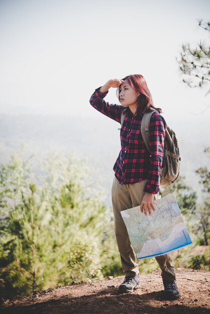 Путешественник девушка ищет правильное направление на карте, путешествуя в поход в гору. Концепция путешествия.