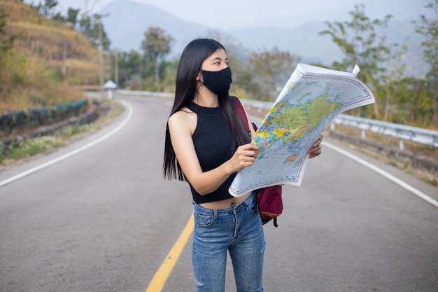 Ragazza viaggiatrice che cerca la giusta direzione sulla mappa