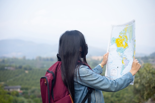 地図上で正しい方向を探す旅行者の女の子