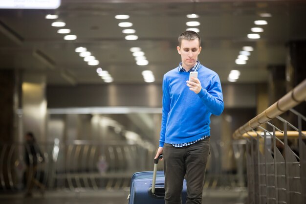 Traveler guy using phone at airport