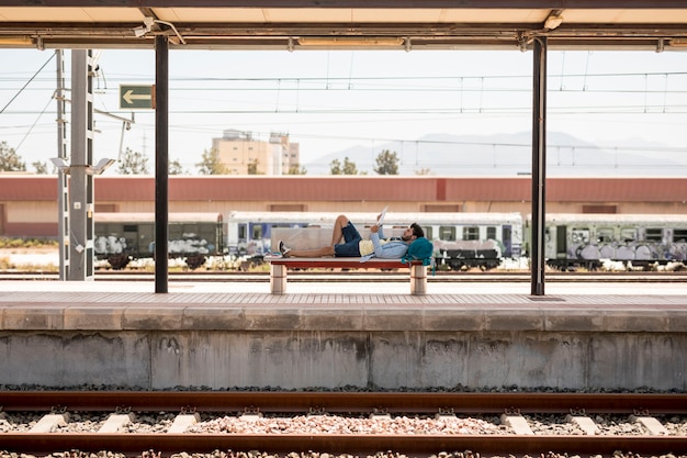 電車を待っているベンチに横になっている旅行者