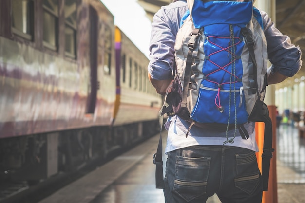 Foto gratuita l'uomo del viaggiatore attende il treno sulla piattaforma ferroviaria