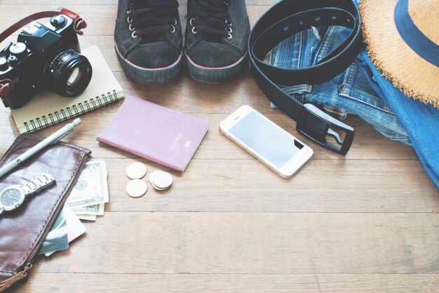 Traveler's accessories, Essential vacation items of young man with passport, camera, mobile device and purse on wood background with copy space