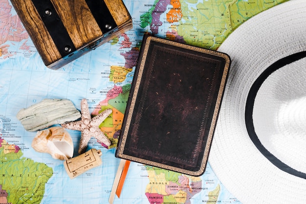 Traveler's diary, sea shell and hat on map