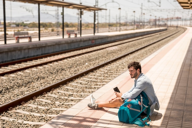 Путешественник сидит на земле в вокзале