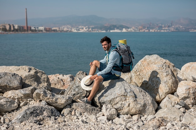 Traveler sitting on rocks at seashore