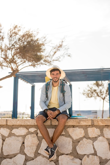 Free photo traveler sitting on a stone fence