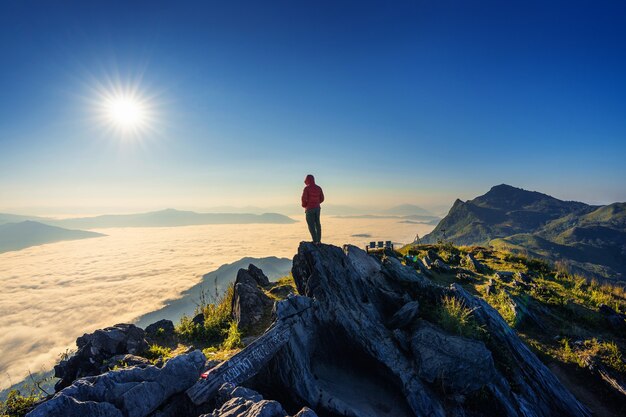 Traveler standing on the rock, Doi pha tang and morning fog in Chiang rai, Thailand.