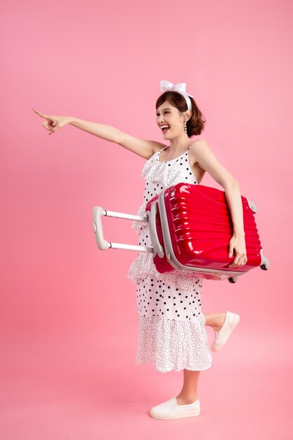 Traveler tourist woman in summer casual clothes with travel suitcase isolated on pink