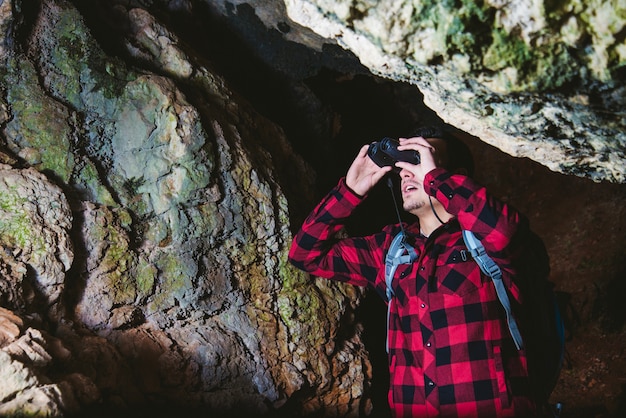 Free photo traveler with binoculars in the cave