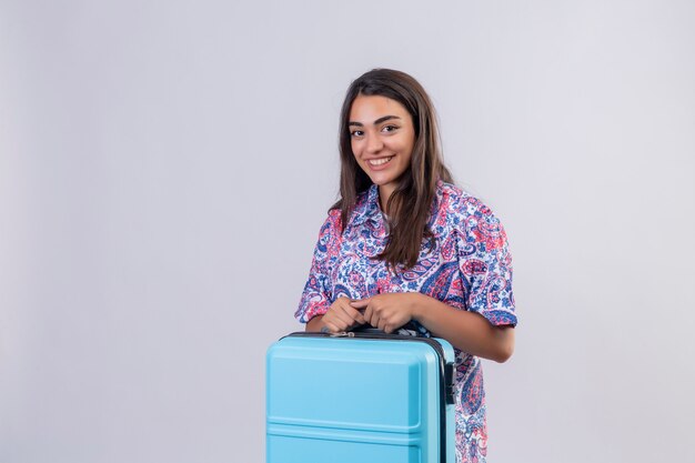traveler woman holding travel suitcase smiling cheerfully, ready to holiday standing on isolated white
