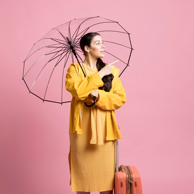 Traveler woman looking away while holding an umbrella