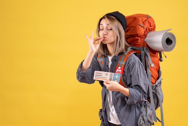 женщина-путешественница с рюкзаком держит билет, делая знак поцелуя шеф-повара