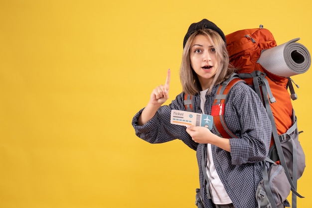 Traveler woman with backpack holding ticket pointing at ceiling