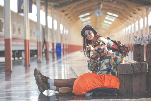 Travelers take pictures of couples while waiting for trains.