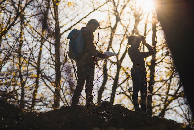 Travelers using a map and binoculars in the forest