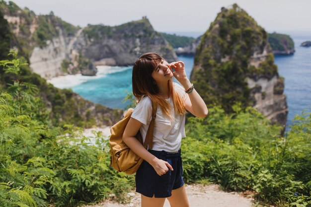 여행 및 모험 개념. Nusa Penida 섬에 인도네시아를 여행하는 백 팩과 함께 행복 한 여자.