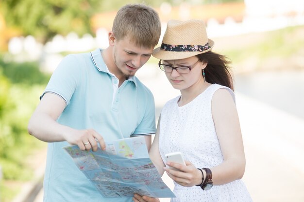 地図や電話で旅行するカップルが旅行で迷子になった