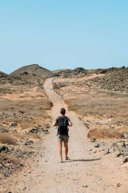 Traveling man on sandy mountain road