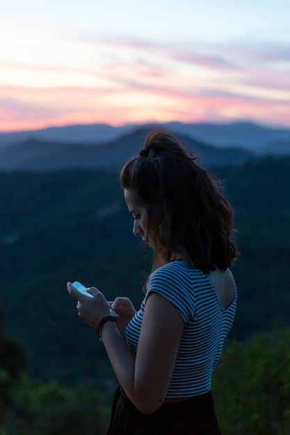 Foto gratuita viaggiatore guardando il suo telefono con le montagne sullo sfondo