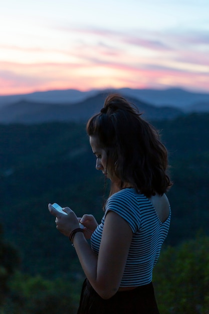 Traveller looking at her phone with mountains in background