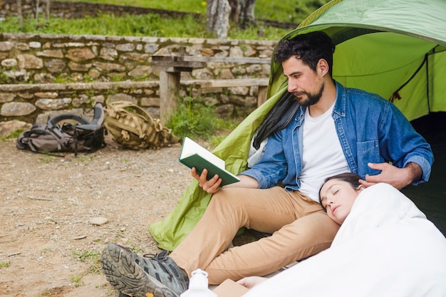 眠っている女性の近くの旅行者の読書