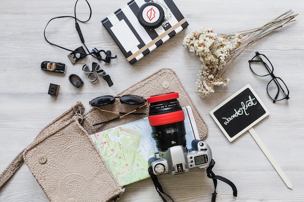 Free photo travelling equipments and wanderlust placard on the wooden desk