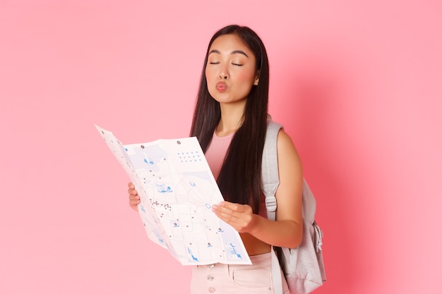 Travelling lifestyle and tourism concept portrait of silly asian girl tourist with backpack and map ...