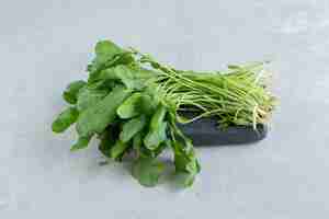 Free photo a tray of fresh watercress , on the marble background.