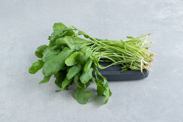 A tray of fresh watercress , on the marble background.