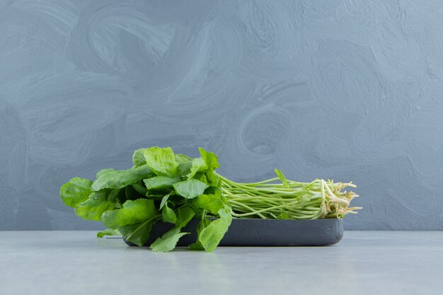 A tray of fresh watercress , on the marble.