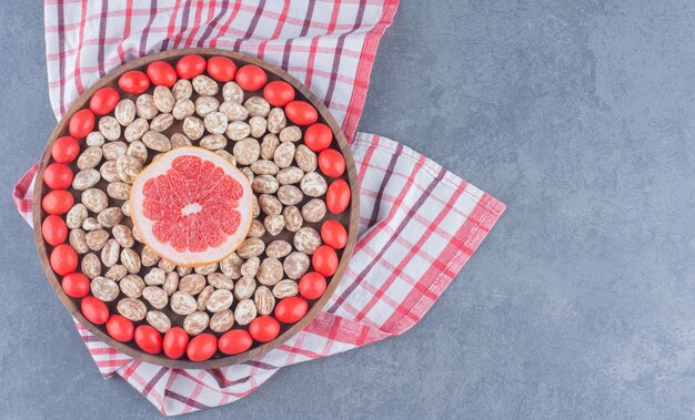 Tray full of cookies and gums with grapefruit in the middle, on the marble background. 