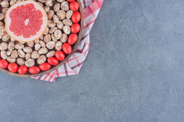 Tray full of cookies and gums with grapefruit in the middle, on the marble background. 