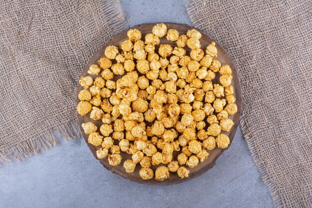 A tray full of popcorn candy and two pieces of fabric on marble surface