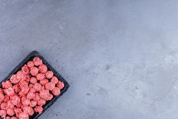 Tray of red popcorn candy on marble surface