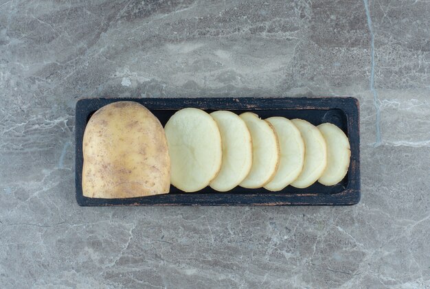 A tray of sliced potato , on the marble table. 