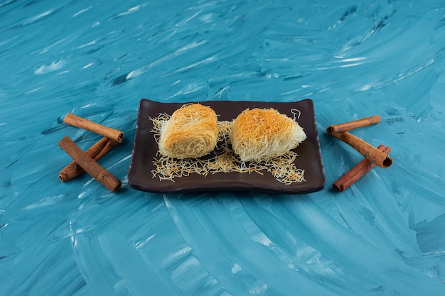 A tray of Turkish delights with cinnamon sticks on a blue background.