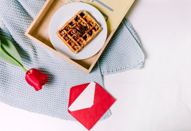 Tray with Belgian waffle and red tulip on scarf 