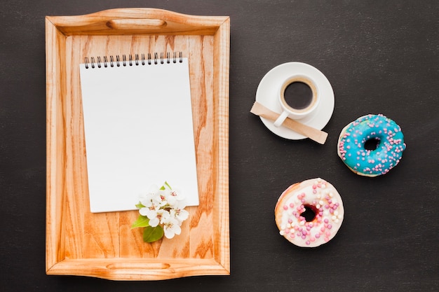 Tray with breakfast and notebook on table